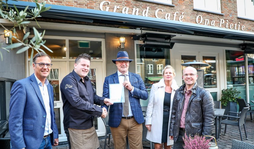 • Burgemeester Henny van Kooten overhandigt het eerste bordje aan Jeroen van Liempt van grand-café Opa Pietje. Links Maarten Mulder.