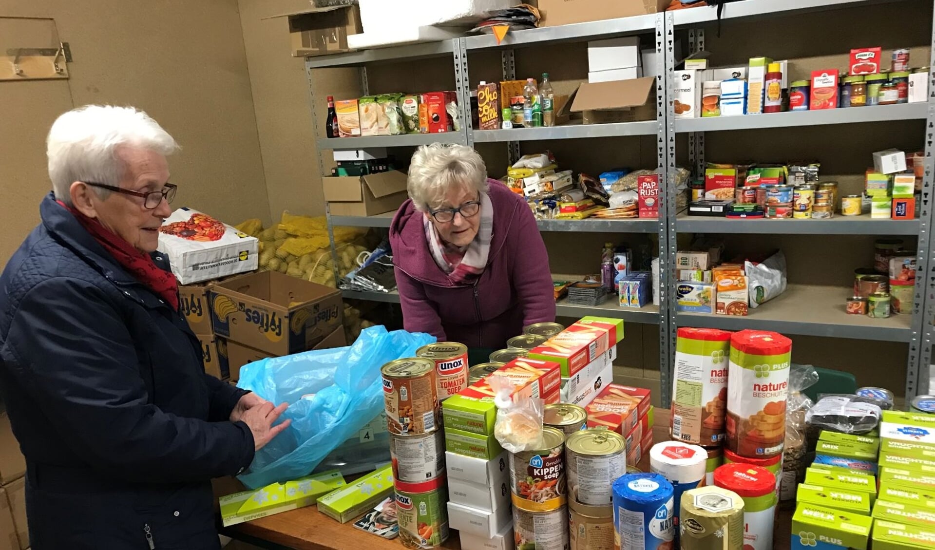 • De vrijwilligers Dini Verburg en Marrie den Hartog sorteren de levensmiddelen voor de pakketten.