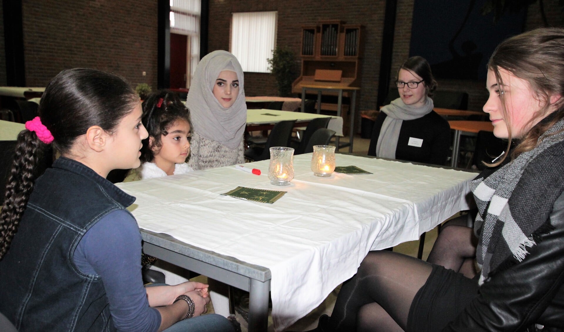 • Leerlingen van het Driestar College aan tafel met drie Syrische meiden uit Krimpen aan den IJssel.