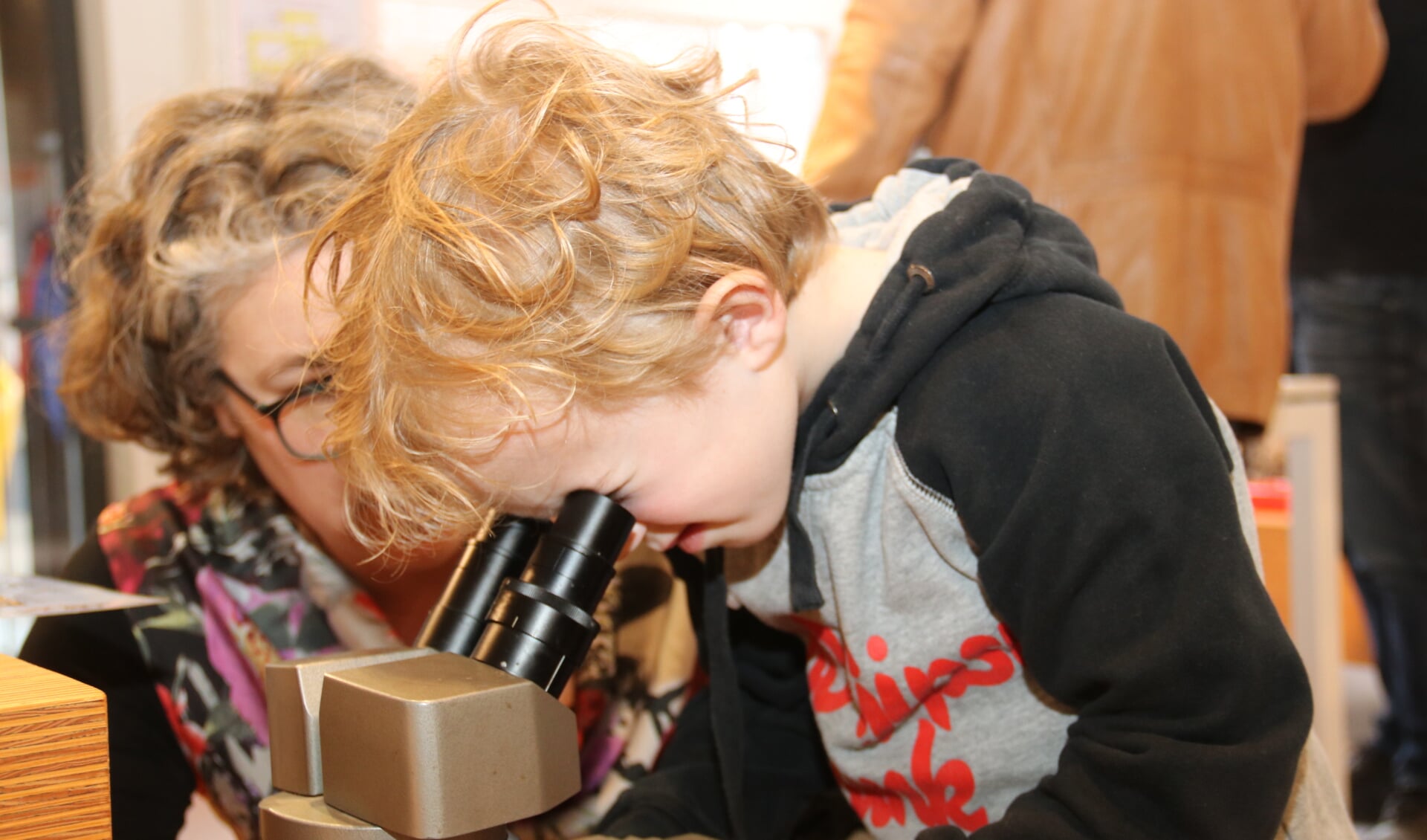 • Een jongetje bekijkt larfjes en kevertjes door een microscoop.