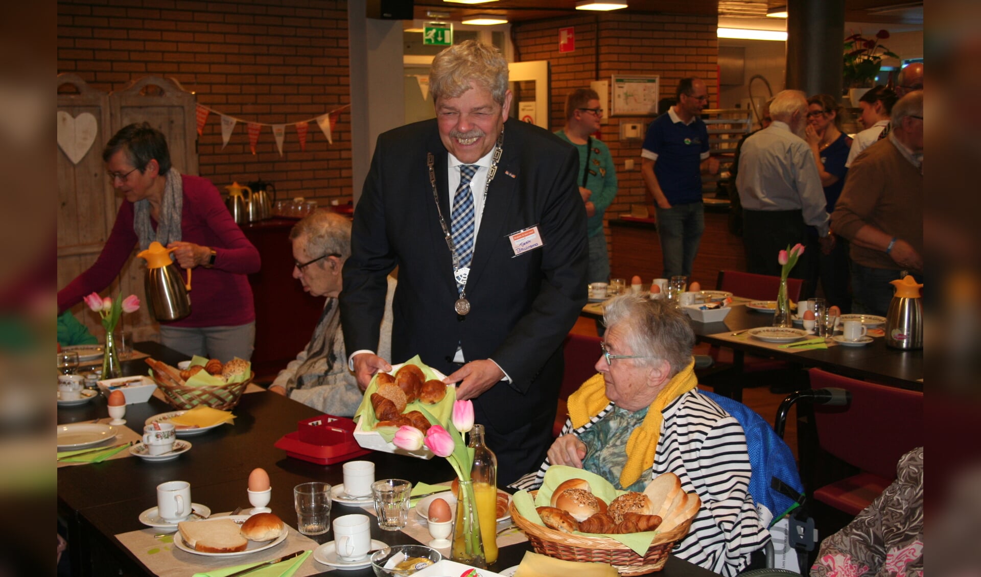 • Burgemeester Tjerk Bruinsma deelt broodjes uit in Huis ter Leede. 