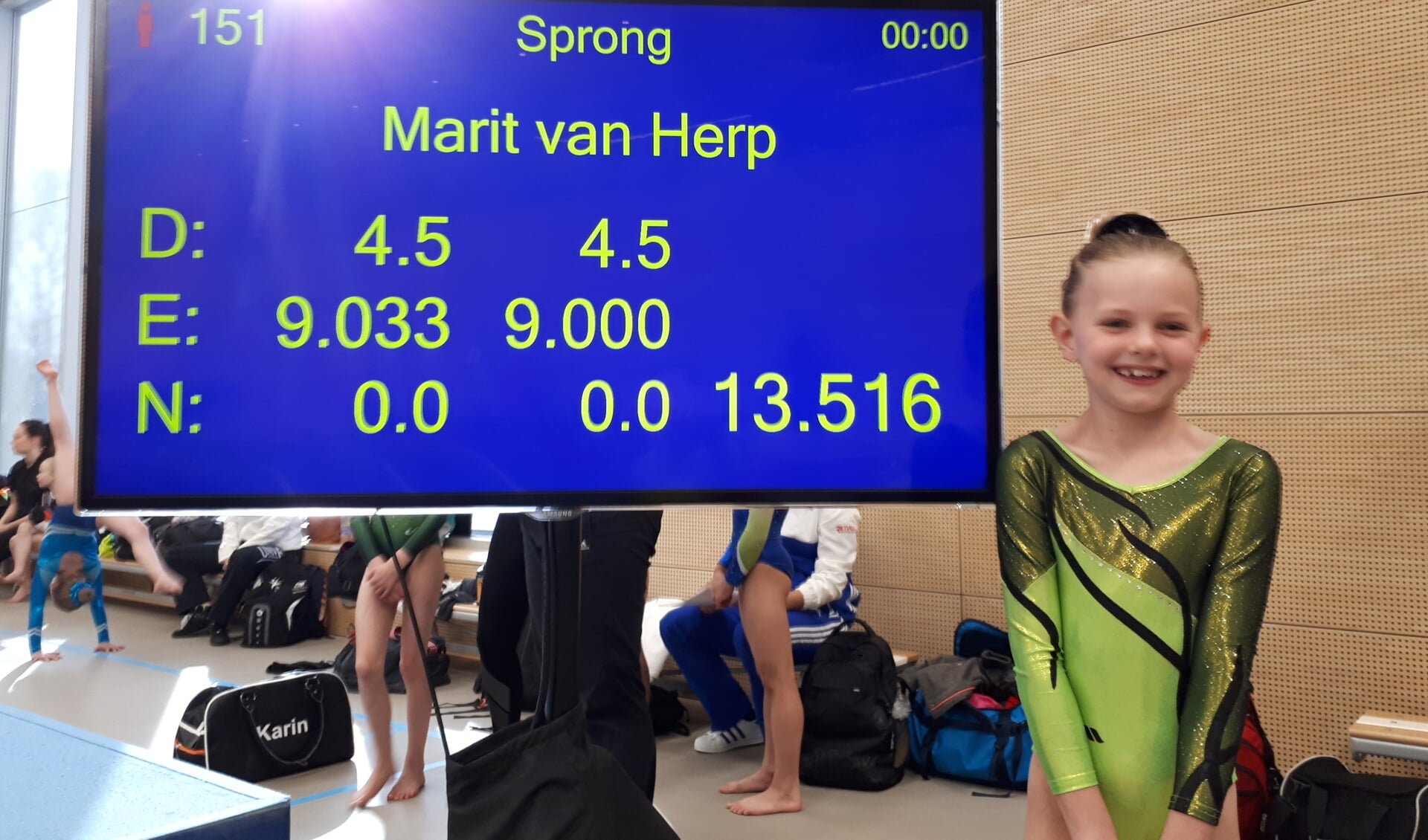 • Marit van Herp bij het scorebord, waar het cijfer op het onderdeel sprong wordt getoond (13.516).