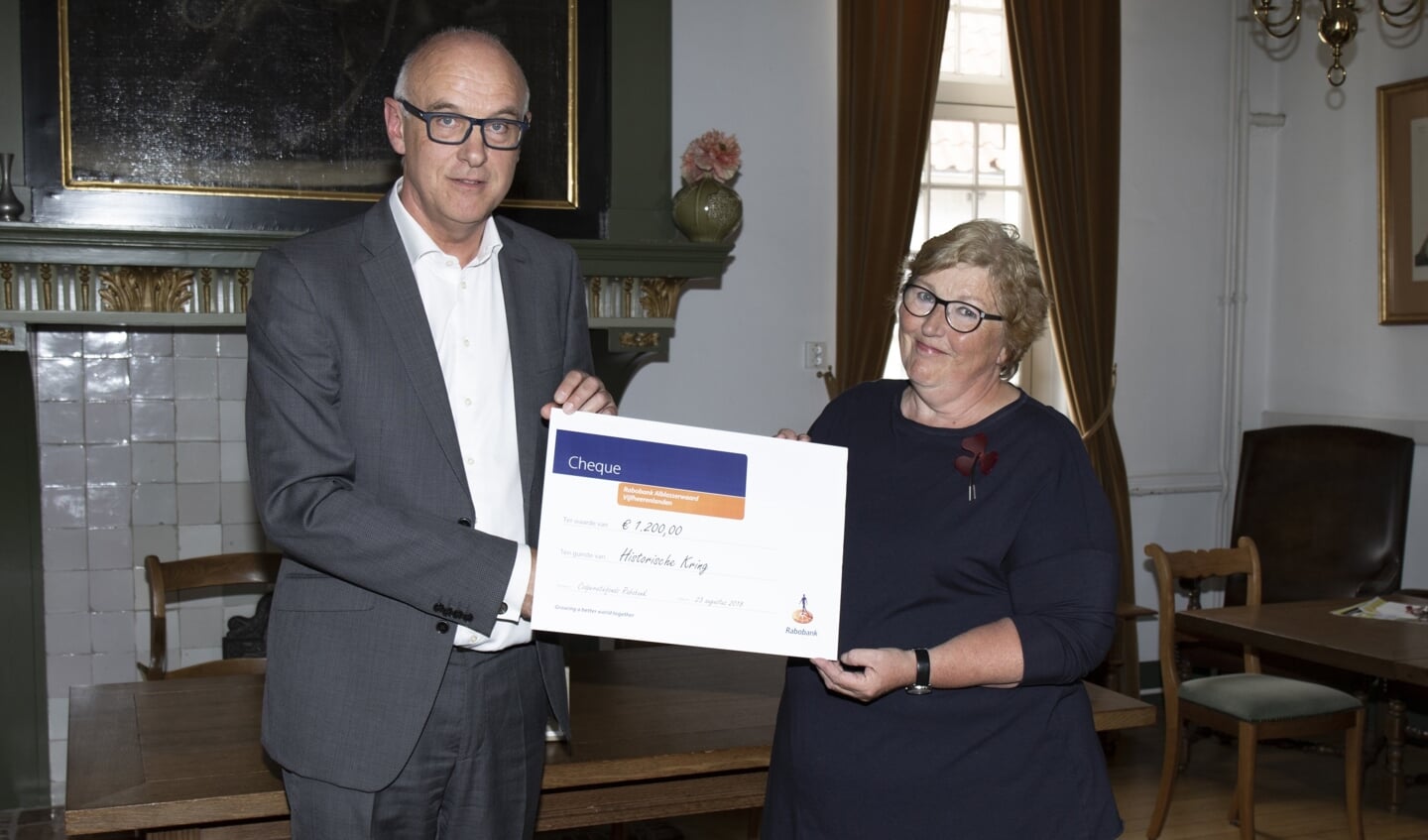 • Joke van Leeuwen, bestuurslid van de eerstgenoemde vereniging, ontvangt uit handen van directievoorzitter Martijn Spijk een cheque ter waarde van 1200 euro.