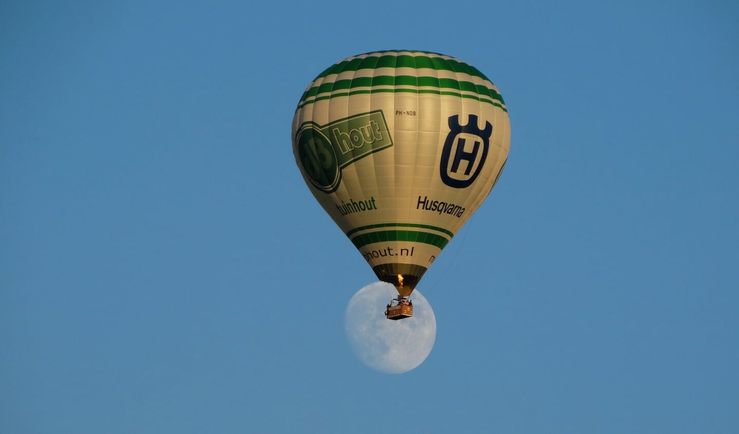 • Luchtballon schuift voor de maan.