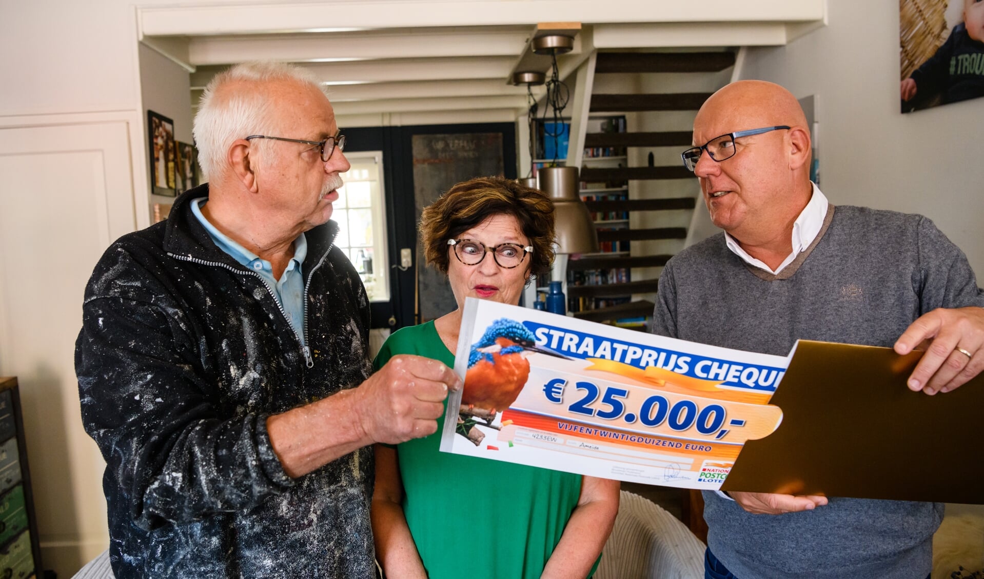 Jan Willem en zijn vrouw uit Ameide worden verrast door Postcode Loterij-ambassadeur Gaston Starreveld met de PostcodeStraatprijs-cheque