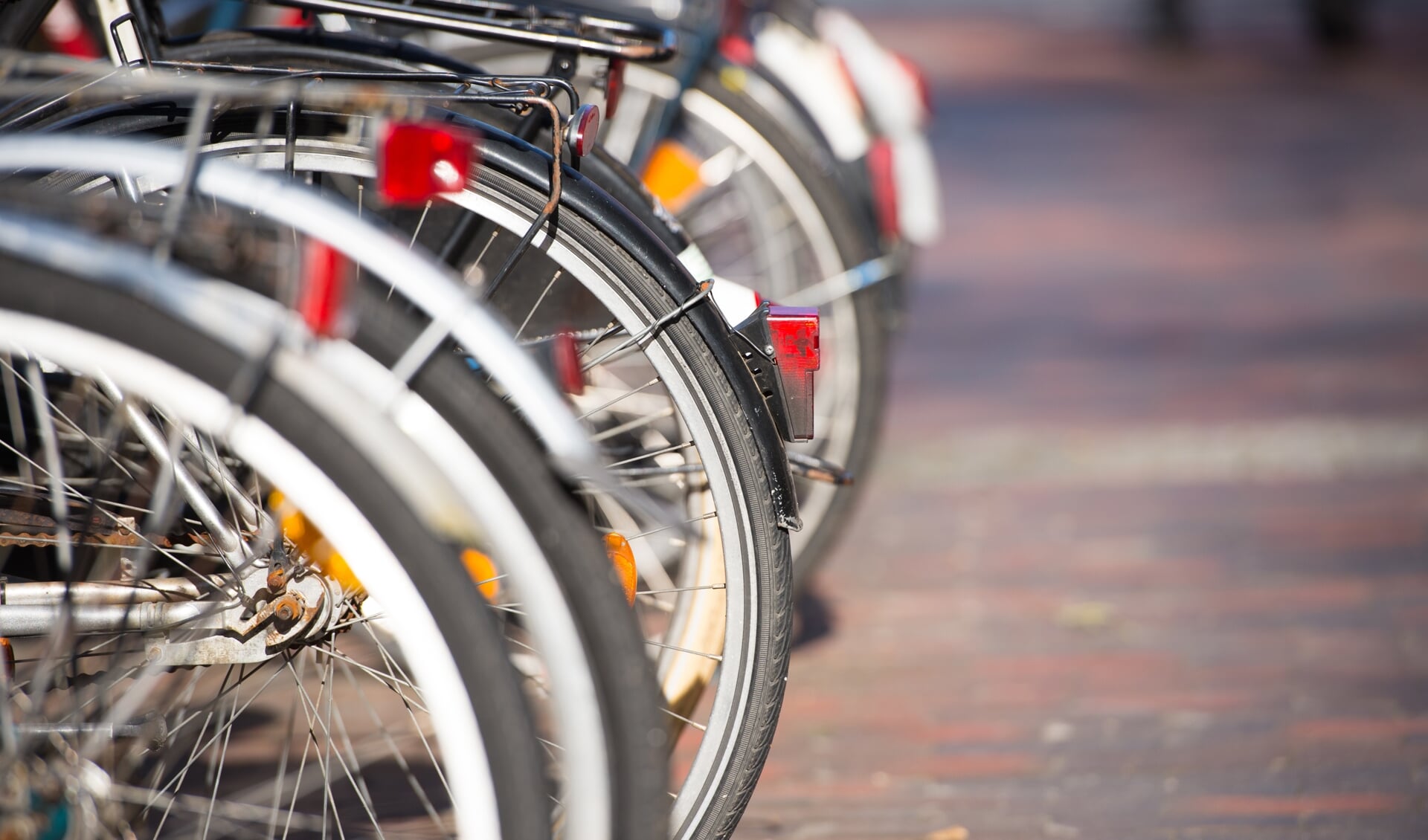 Close up of bicycles wheels parked in a row in the city, blurred background and copy space.