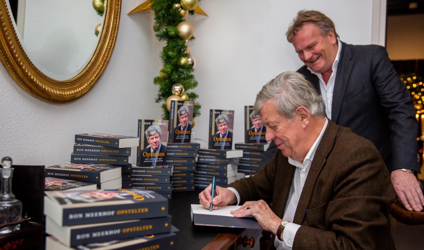• Ivo Opstelten signeert, Dick Brandwijk kijkt toe.