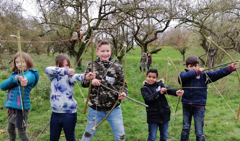 Kinderen schieten met hun eigengemaakte pijl en boog.