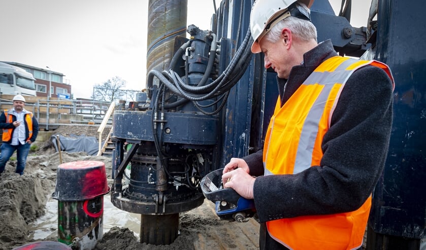 • Projectwethouder Anthon Timm bedient de knoppen en drukt zo de eerste funderingspaal de grond in.