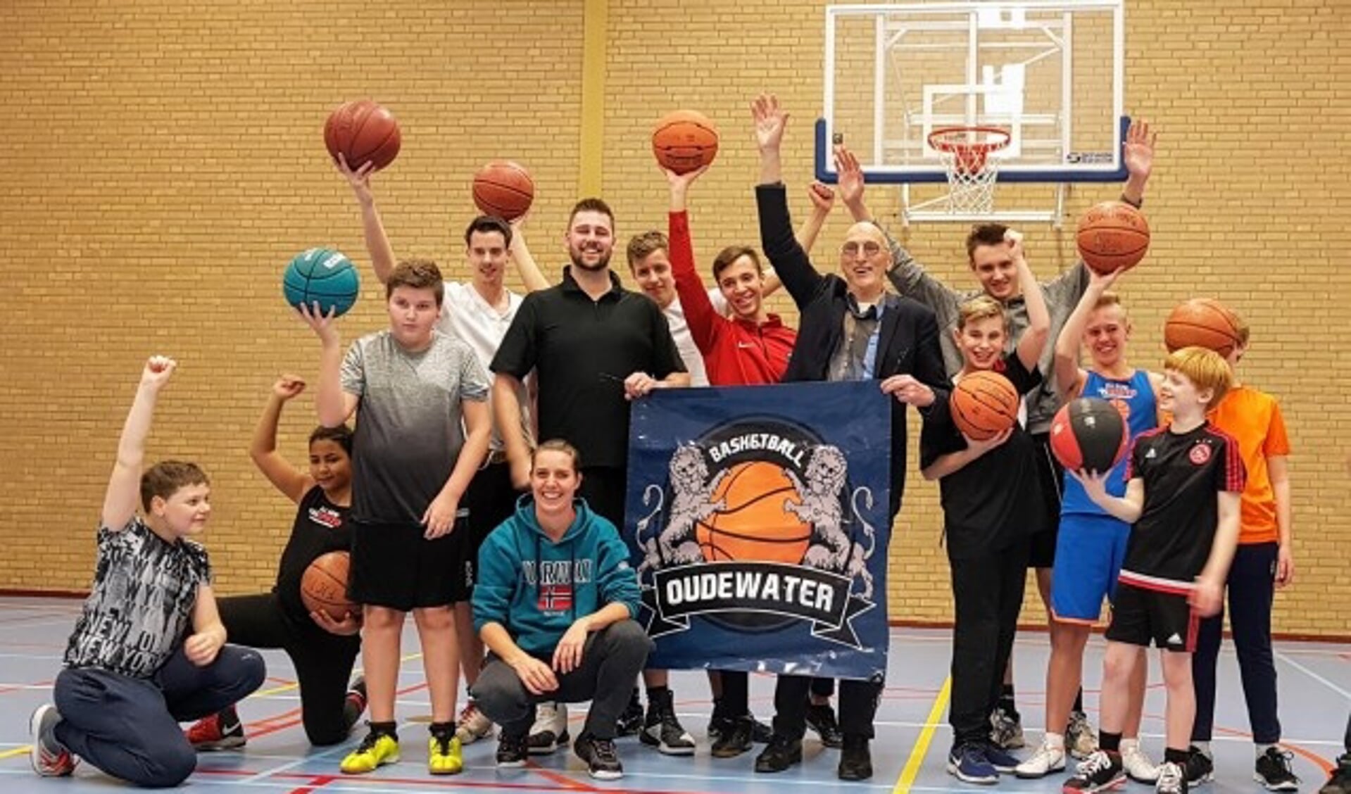 Wethouder Walther Kok te midden van de basketballers, blij met de twee aangeschafte wedstrijdbaskets voor sportzaal De Eiber. (Foto: Ellen van Leeuwen)