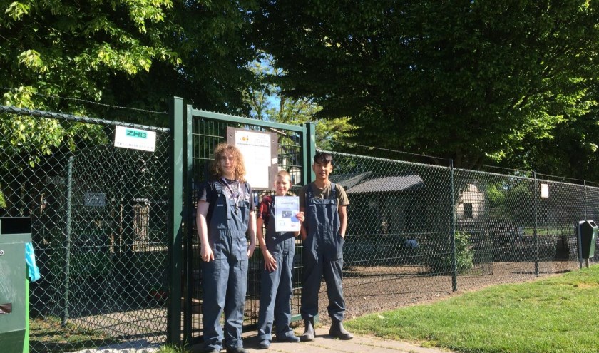 • Drie leerlingen van De Brug staan bij de kinderboerderij met het bewijs van adoptie van de dwerggeiten.