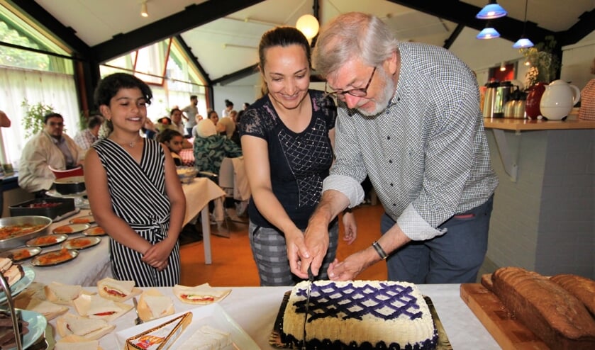 • Henk van der Sijden snijdt de taart aan tijdens het 'bedankfeestje' dat voor hem was georganiseerd.