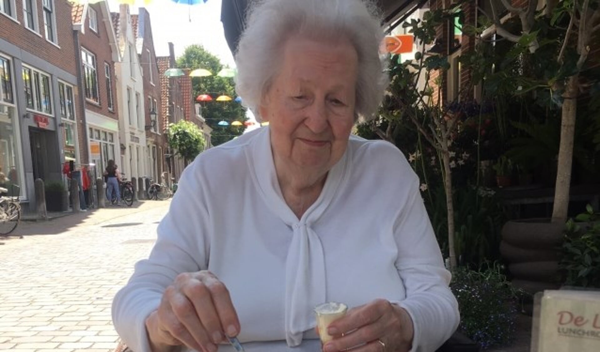 Mevrouw Van Breukelen geniet van het mooie weer, de fleurige binnenstad  én koffie met gebak. (Foto: vrijwilligster Nel van Rooijen) . 