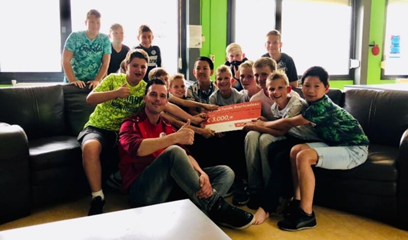 • Wouter Rijneveld met enkele jongeren en de cheque.