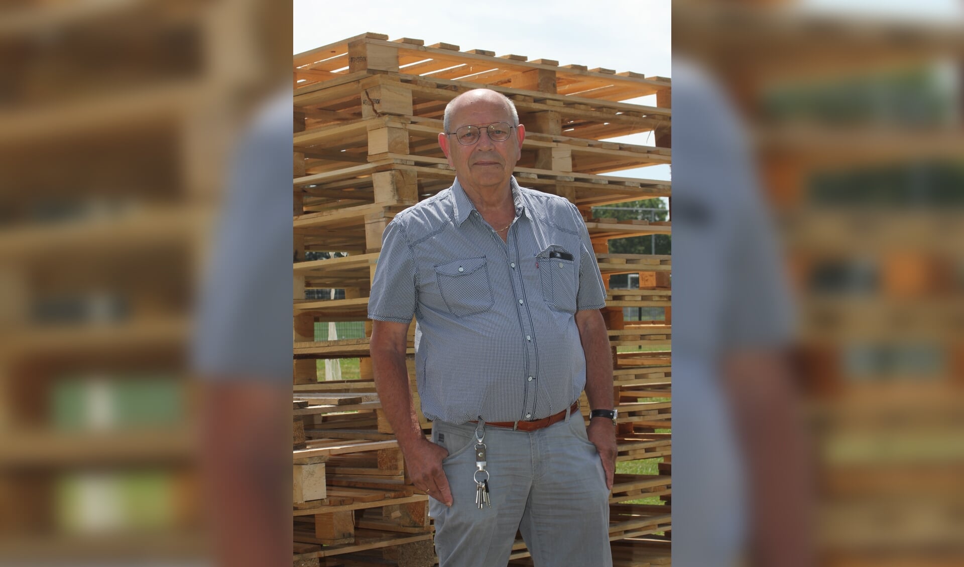 • Henk Knol voor een grote stapel pallets waar de kinderen mee kunnen gaan bouwen.