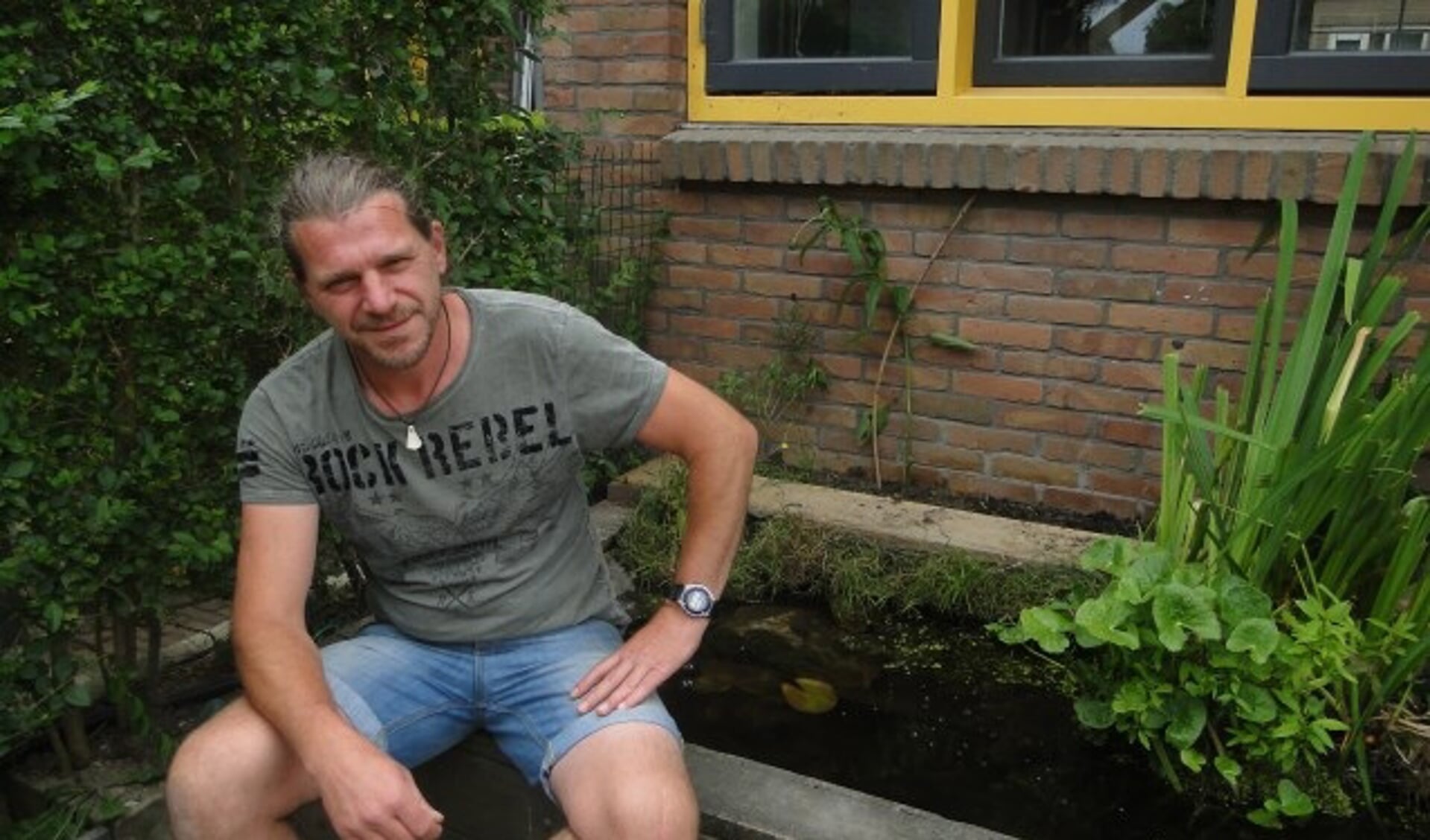 Dennis Mijderwijk in de zon bij zijn vijvertje in de tuin. ''Ik ben al een beetje bezig met meer groen.'' (Foto: Leo Polhuys) 
