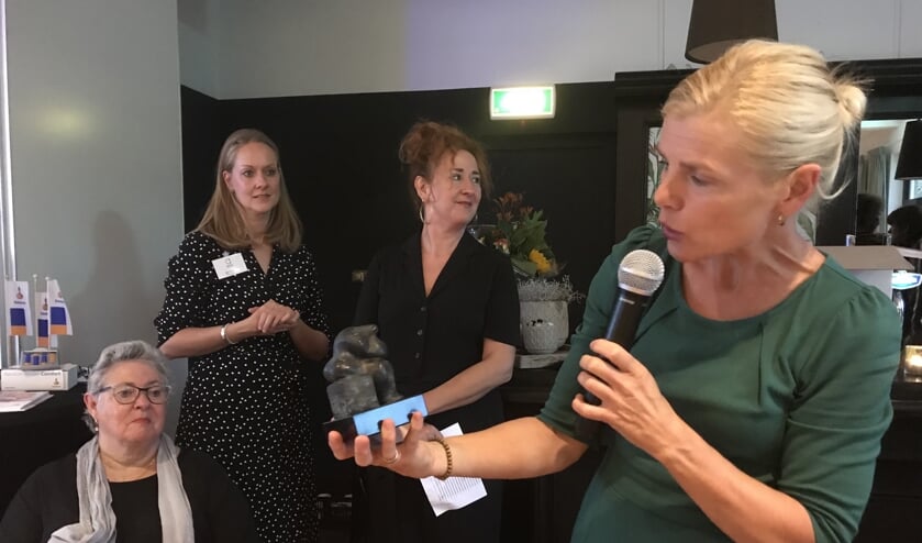 Wethouder Jorritsma met het beeldje van het alzheimercafé, helemaal links op de foto Henny Verhoeven.