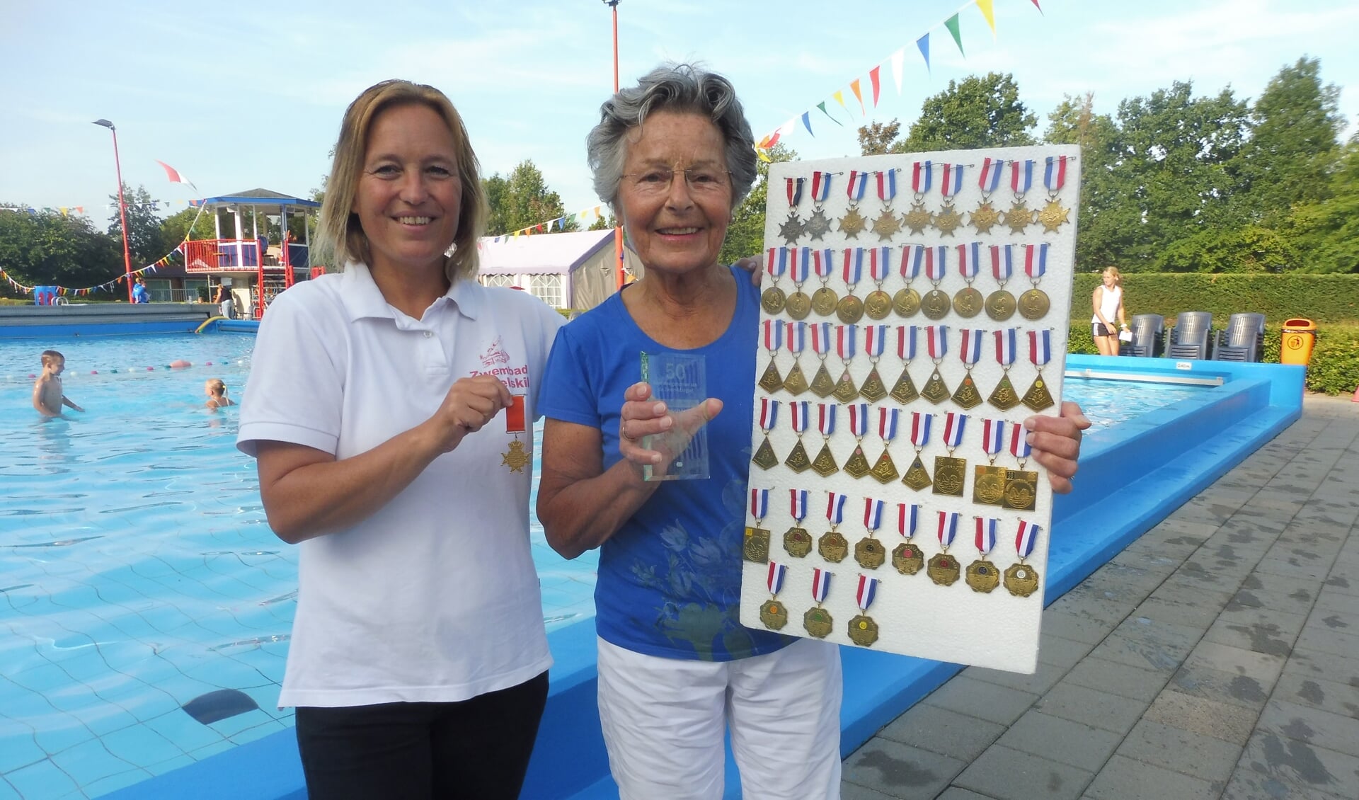 Ria van Bennekom krijgt haar 50e medaille èn oorkonde van de zwembond voor haar 50e zwemvierdaagse uitgereikt door Elmy van Maastrigt