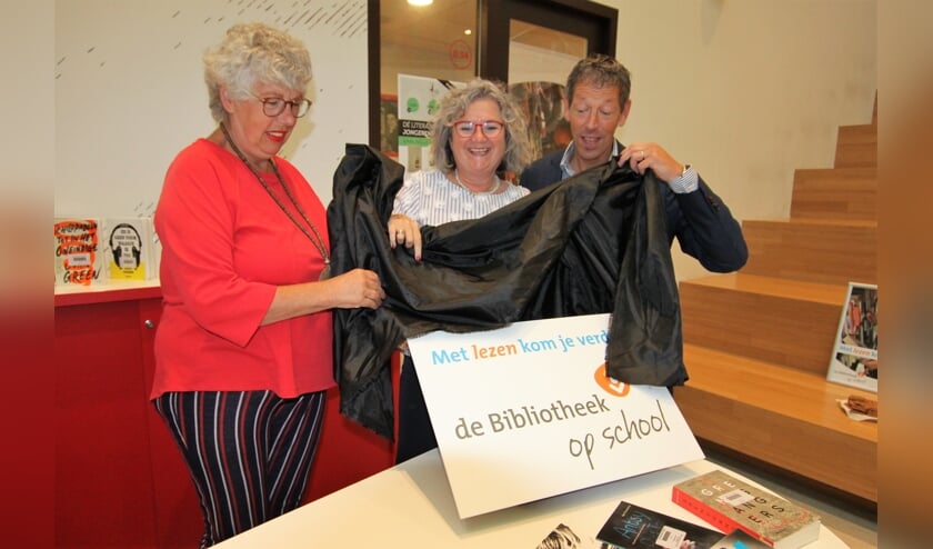 • Conny Reijngoudt, Kirsten Jaarsma en Ad Keller onthullen het logo van de bibliotheek in de school.