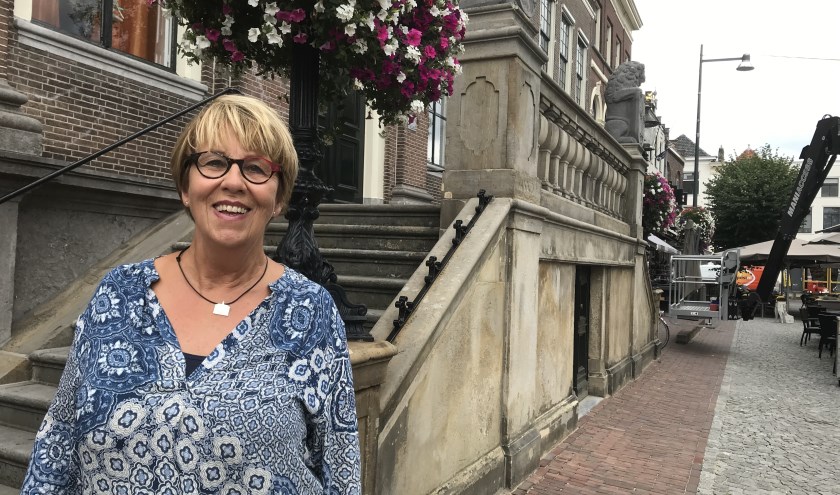 Bea Flierman (66 jaar) voor het stadhuis, om haar nek het zilveren miniatuurraadhuis dat ze cadeau kreeg.