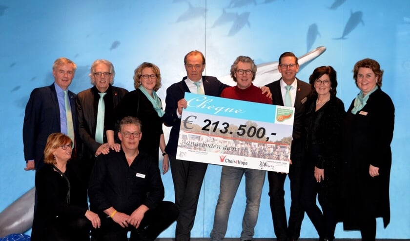 • prof.dr. Casper van Eijck (met de cheque in handen) met naast hem Peter Overduin (in rode trui) en enkele bestuursleden van beide koren.