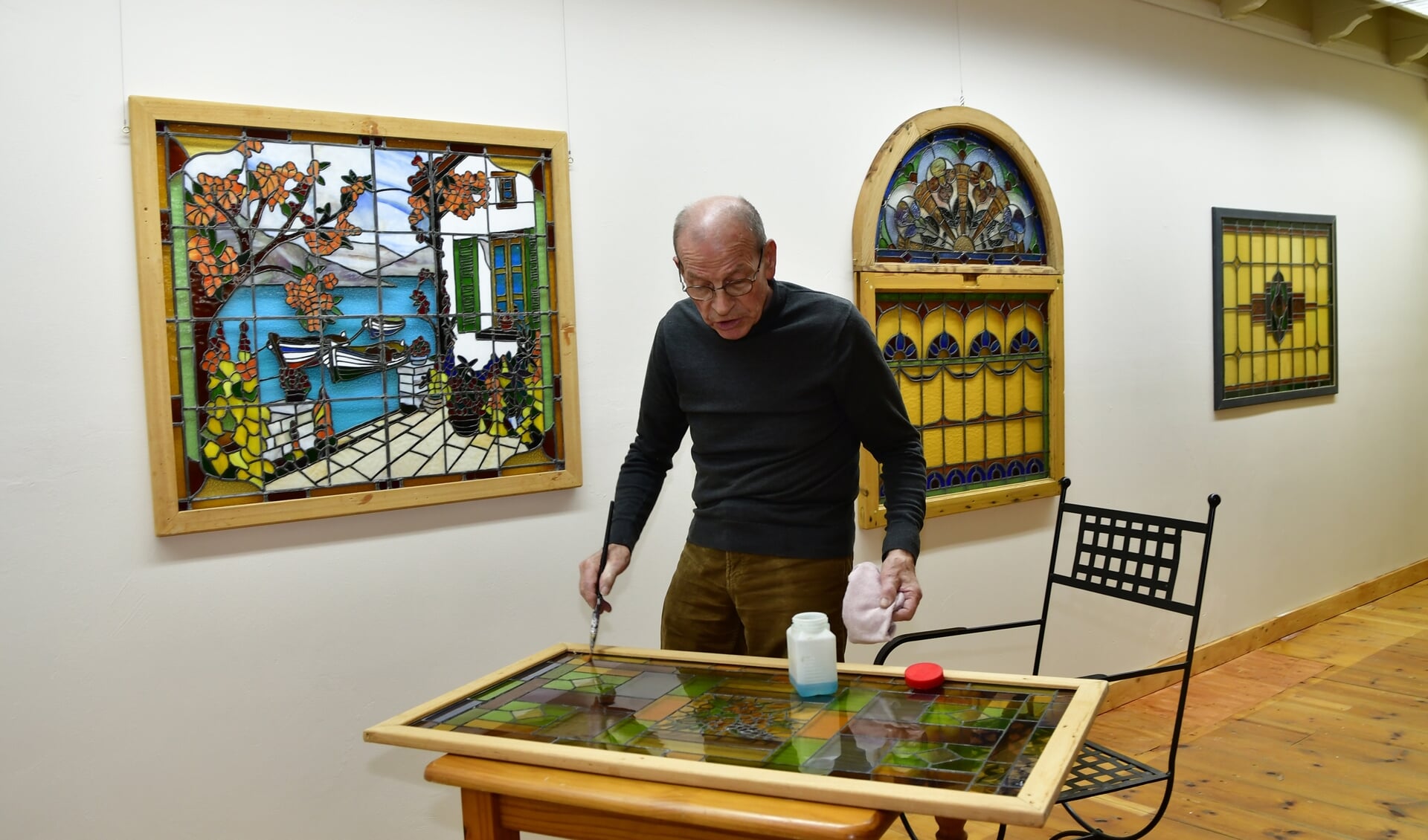 • Gerrit van IJzeren in de nieuwe galerie, bezig met één van zijn panelen. 