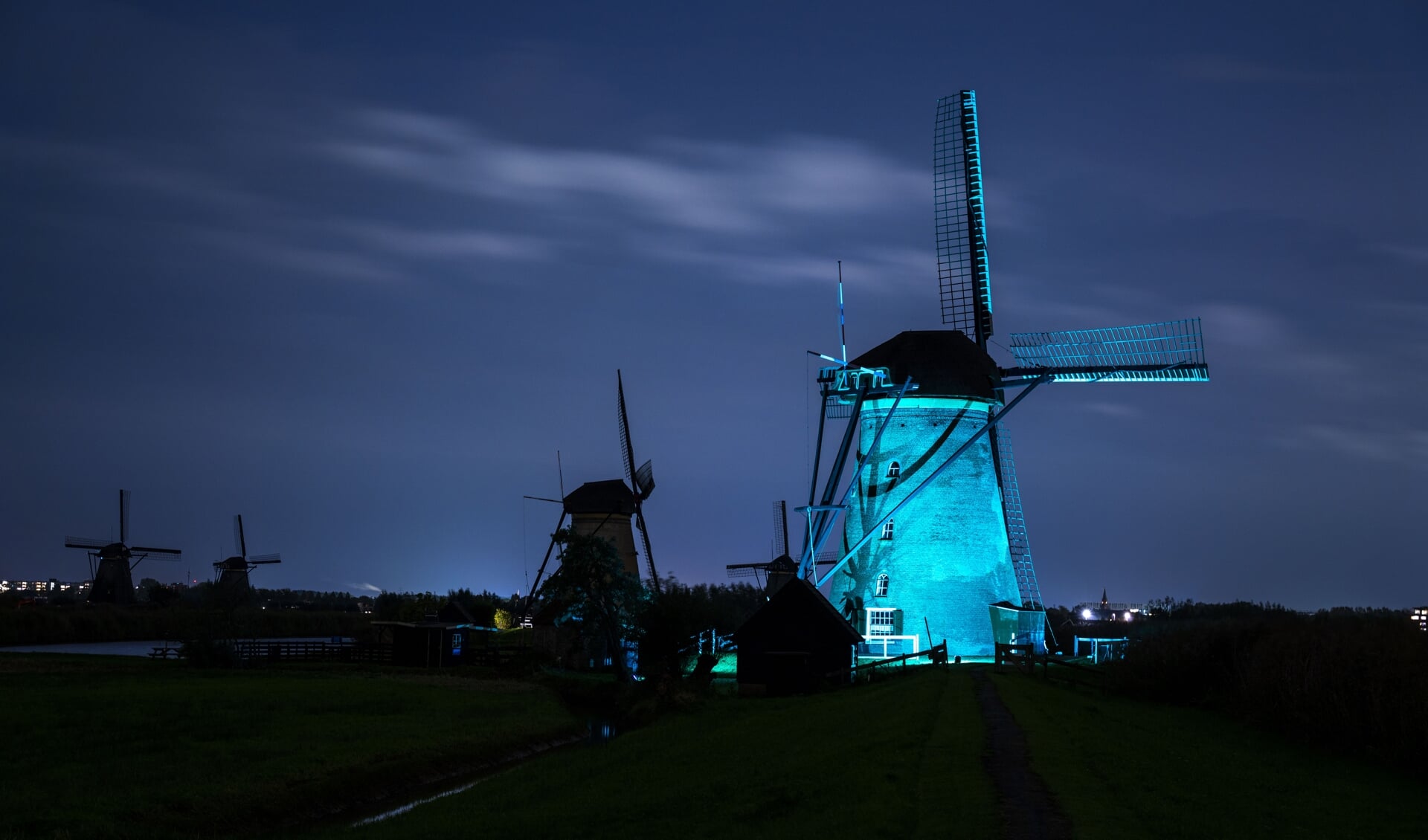 • Een blauw verlichte molen in Kinderdijk. 