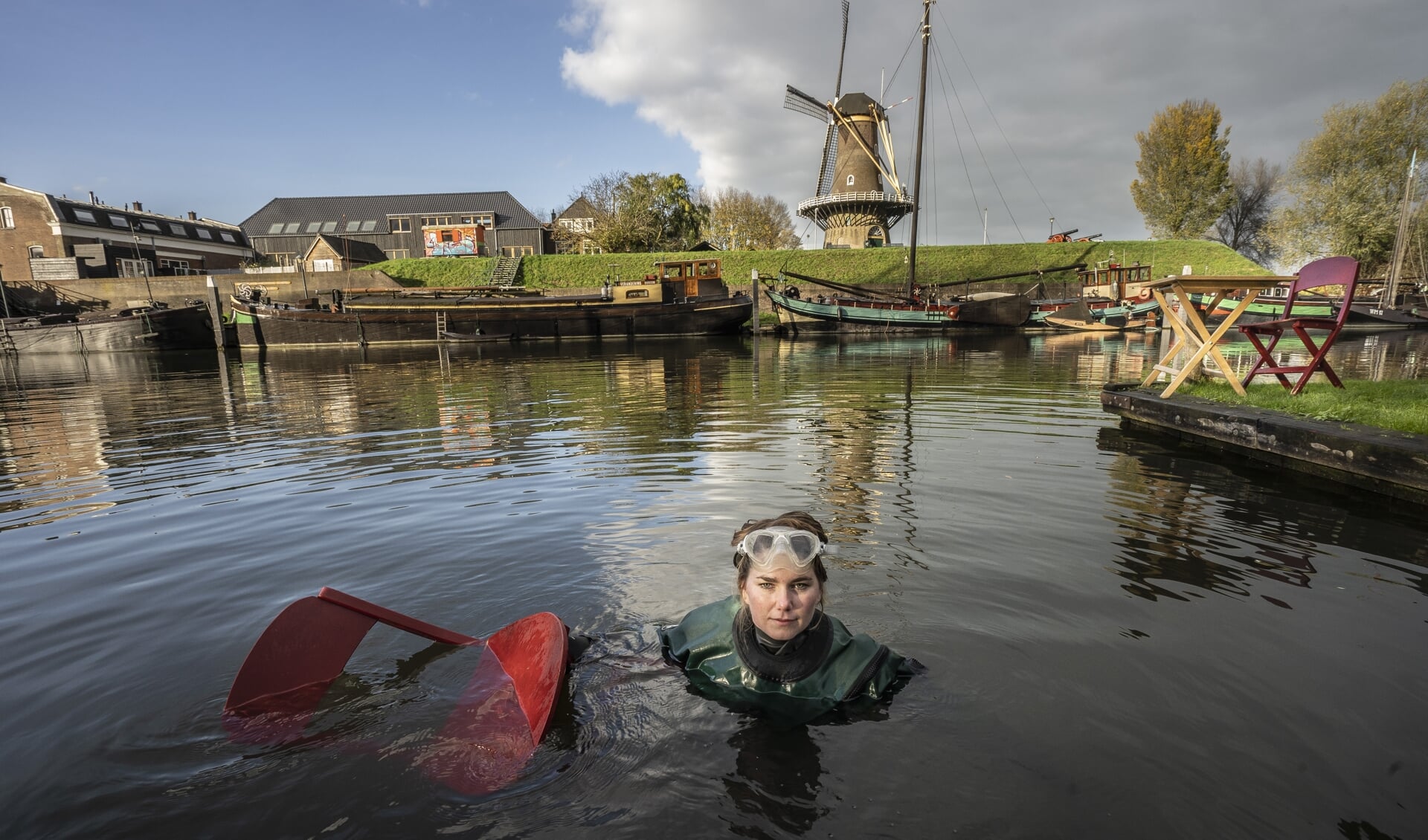 • Duikster Brenda in het water van de Linge, met op de achtergrond de Gorinchemse molen Nooit Gedacht. In de Noordzee dook ze naar plastic.