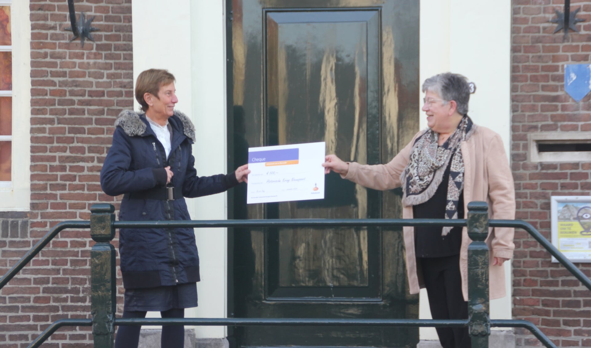 Ria de Jong-Pek overhandigt de cheque aan Adrie den Hartog
