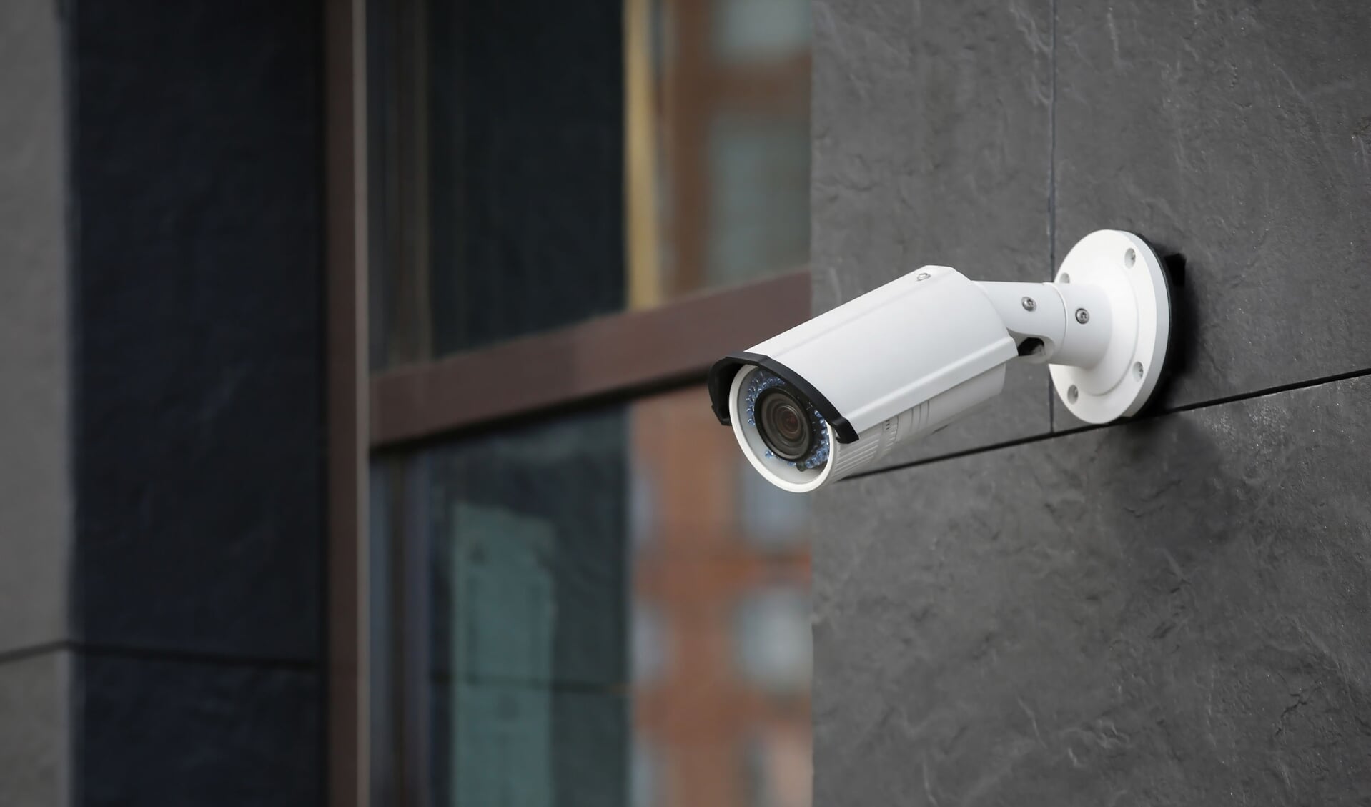 Modern CCTV camera on wall of building outdoors