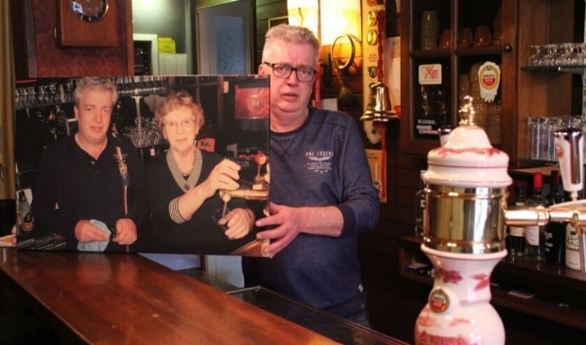 <p>Gerrit de Jong met een foto waarop wijlen zijn moeder staat, die lang actief was in Maurikse horecagelegenheid. (Foto: Henk Jansen)</p>