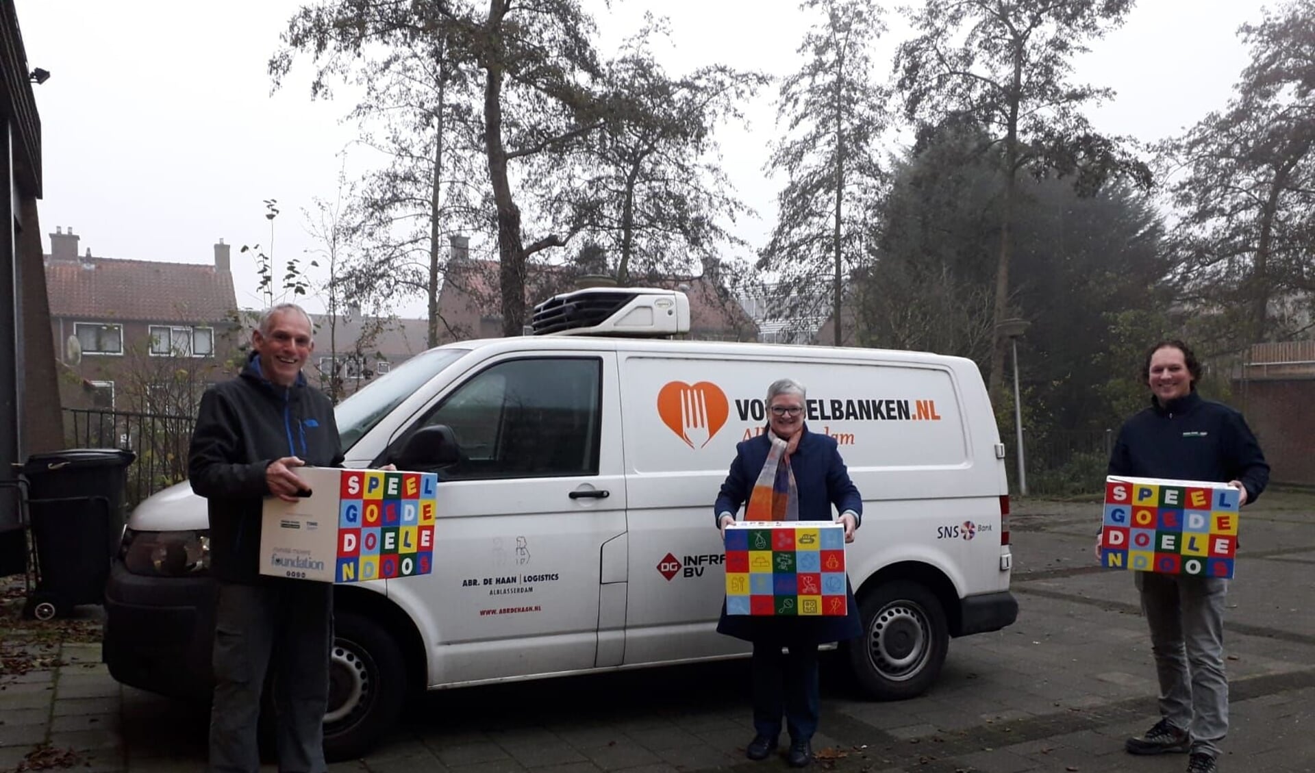 • Ron van Zeggeren (bestuurslid van de Foundation) en Janco Romeijn (Mondial R. Vlot & Zn. Verhuizingen) overhandigen de Speelgoededoelendozen aan Anke van Veen van de Voedselbank Alblasserdam.