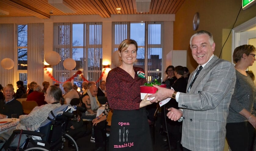 • Wethouder Marcel Verweij overhandigt Rian Kolf een grote doos chocolade voor bij de koffie.