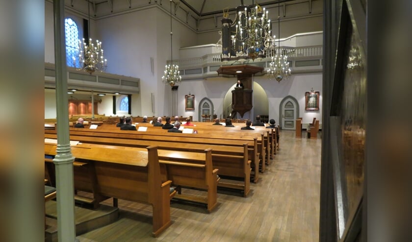 • Beeld van de vrijwel lege Grote Kerk. Alleen de ambtsdragers zitten verspreid in de kerk.