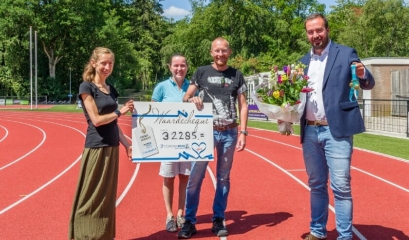 Emy Theunissen en Irma en Dennis Vangangel overhandigen de cheque op de atletiekbaan in Apeldoorn. (Foto: Tony Buijse)