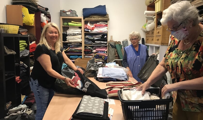 • Vrijwilligers Textielatelier het Puttertje sorteren stof voor mondkapjes.