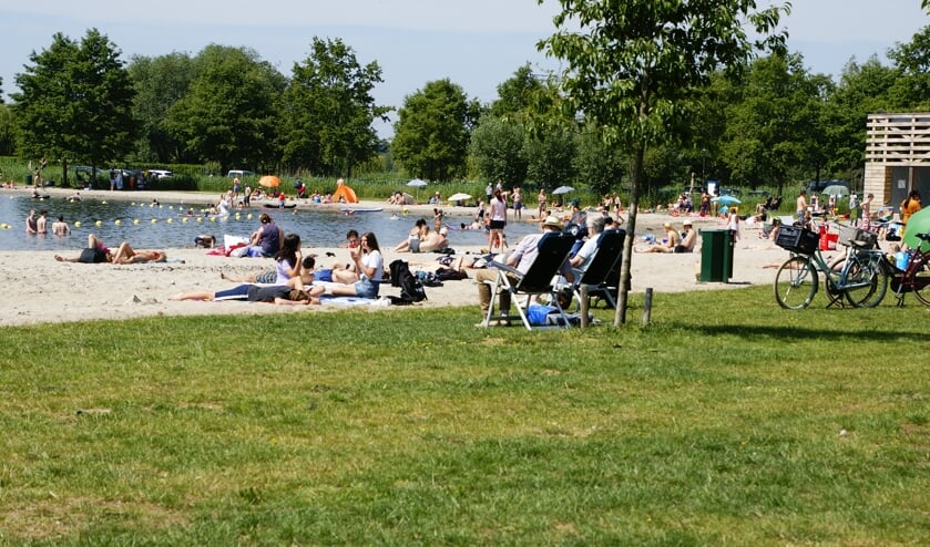 • Dagjesmensen genieten bij de surfplas van het mooie weer.