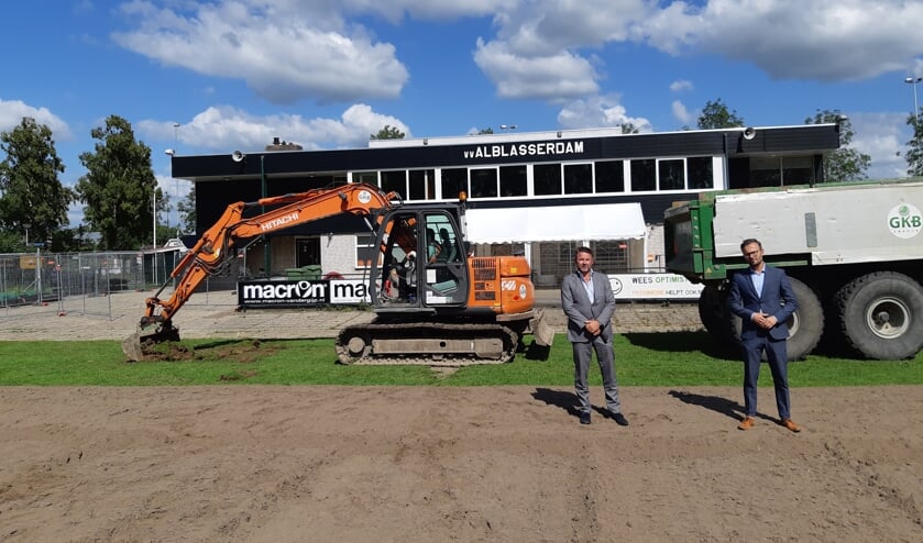 • Wethouder Arjan Kraijo (rechts) en de voorzitter van vv Alblasserdam, Arjan Maat, groeven samen een stukje van de toplaag van het veld af.