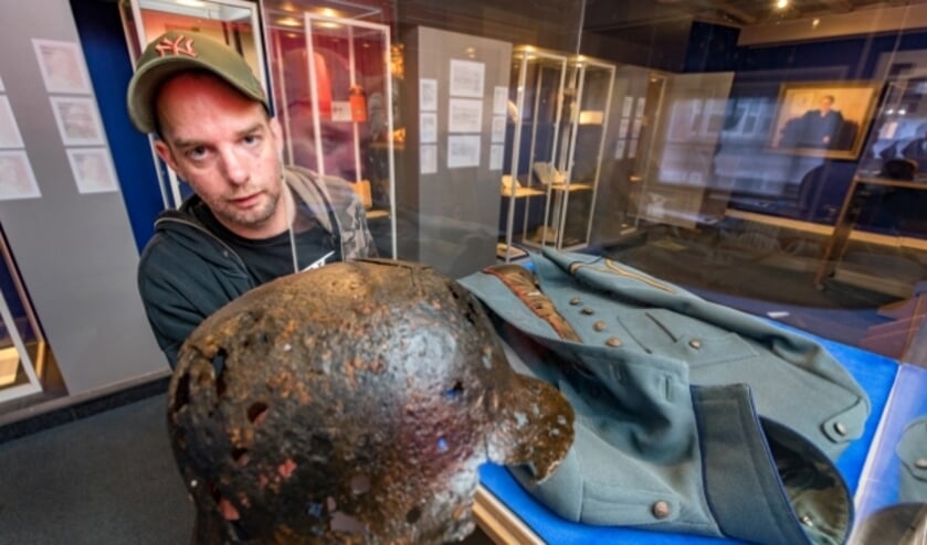 Maarten Meijer met de Duitse legerhelm waar het allemaal mee begon naast de vitrine met het jasje van Boudwijn. (foto: Jan Bouwhuis)
