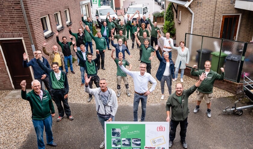 • Het team van Den Hoed Aannemers met het jubileumbord.