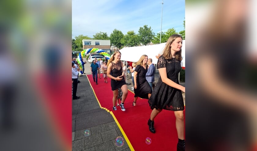 • De geslaagden en hun familie over de rode loper.