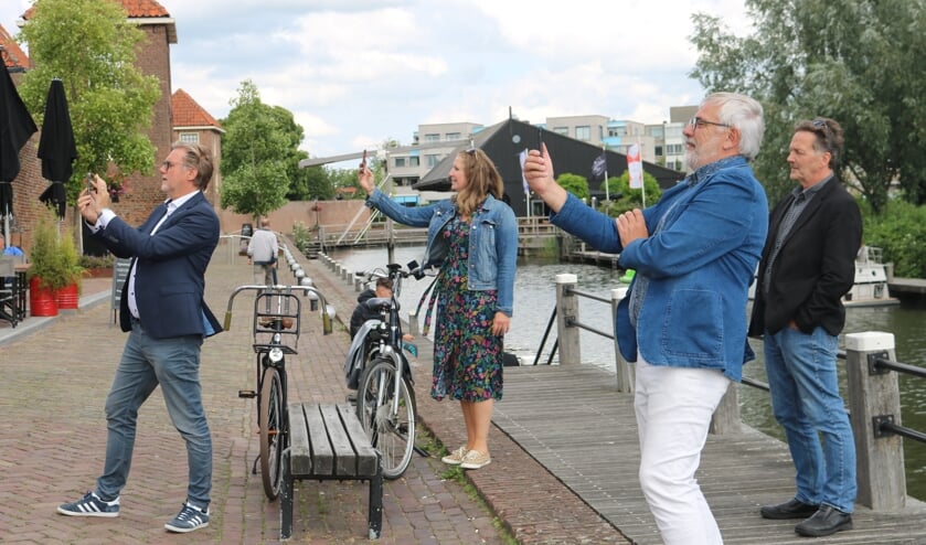 • Rob Smouter en Mirja van Dijk van Leerdamglasstad.nl, Wethouder Cees Taal en raadslid Teus Meijdam staan op de Zuidwal om met de app de Steigerpoort terug te plaatsen op zijn oude plek.