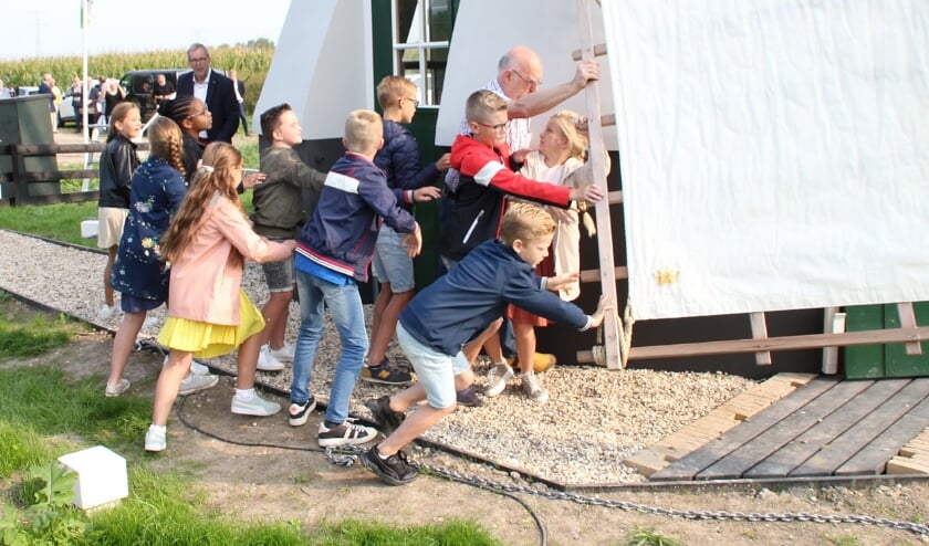• De kinderen geven een zwaai aan een wiek van de molen.