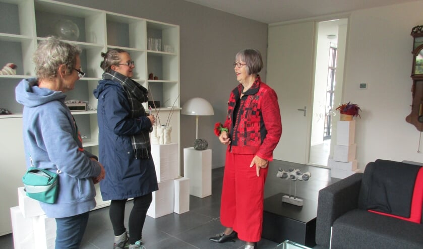 • Margot Odijk in gesprek met twee bezoeksters van haar huiskamerexpositie met vilten objecten.