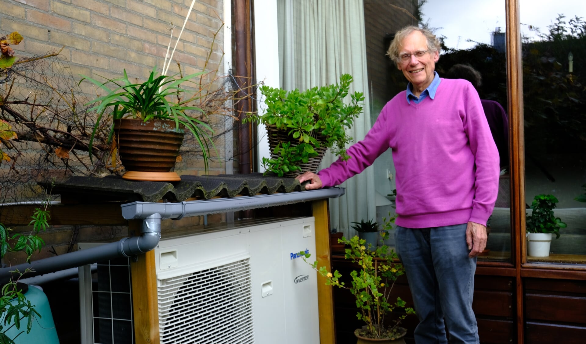 • Dick Biesta bij de warmtepomp in zijn achtertuin.