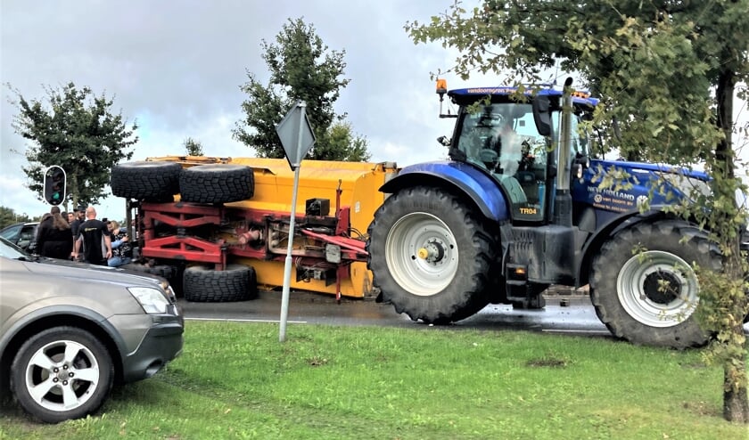<p>De gekantelde aanhanger. Links op de foto wordt de hevig geschrokken bestuurster van de personenauto getroost.</p>