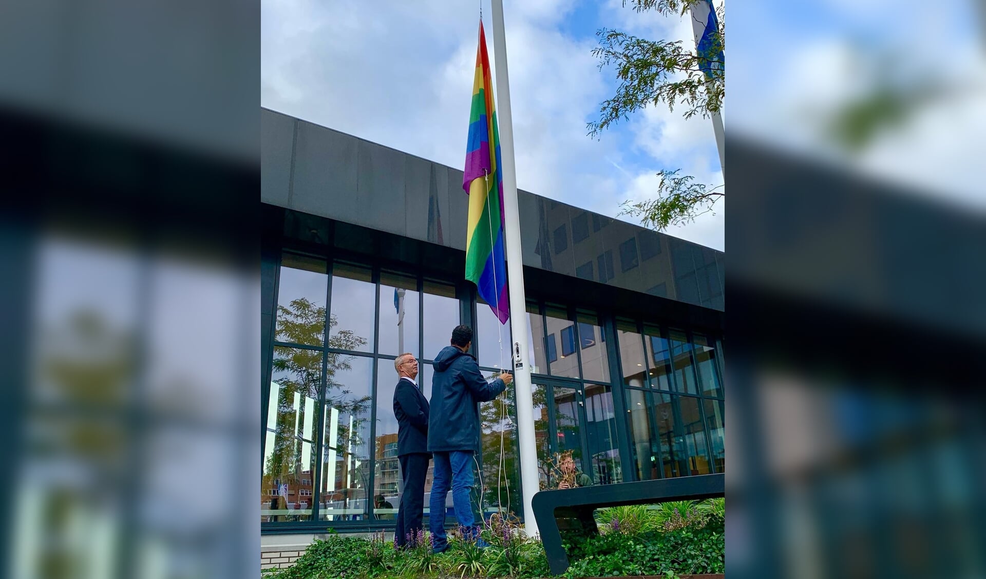 • Wethouder Marc Wilson hijst de regenboogvlag op Coming Out Dag.