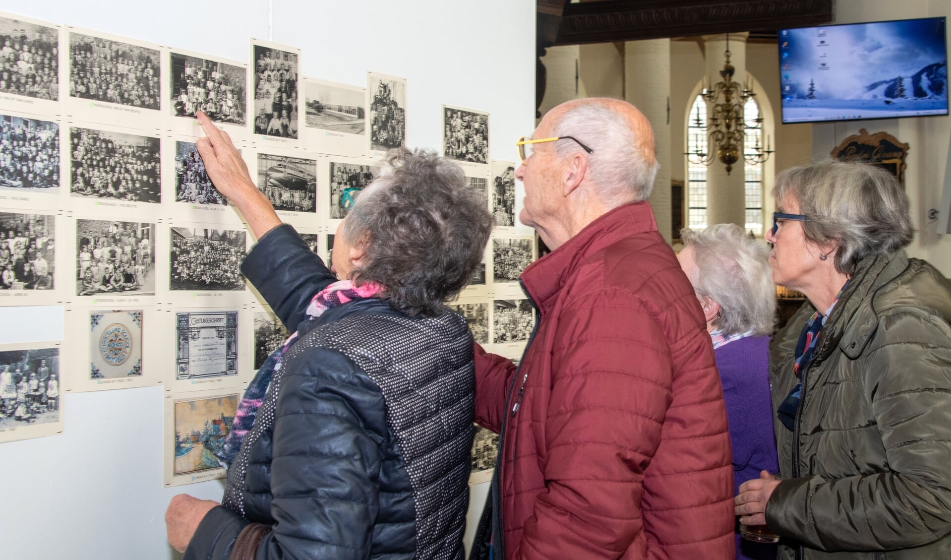 • Bezoekers bekijken de oude schoolfoto's in de Barbarakerk.