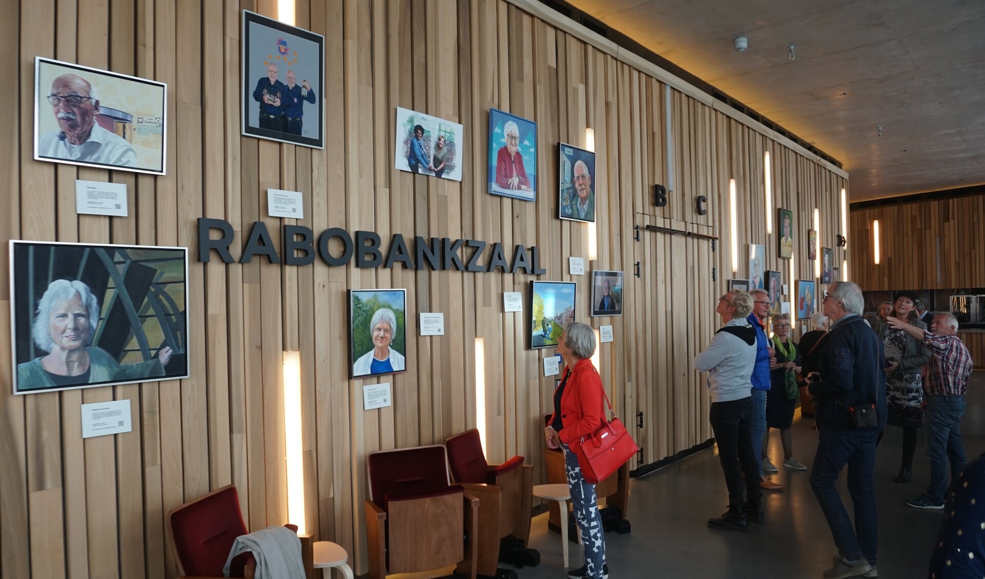 In de foyer van theater DE KOM hangen portretten van mensen die in de stad een belangrijke rol hebben gespeeld.