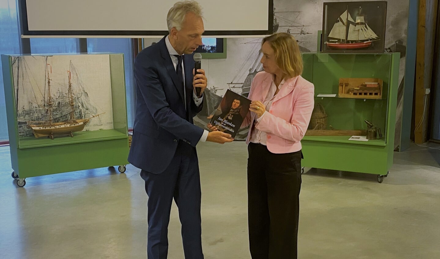• Sjors Fröhlich overhandigt het boekje 'Jan Blanken en de Vijfheerenlanden' aan burgemeester Milène Junius van Hellevoetsluis.